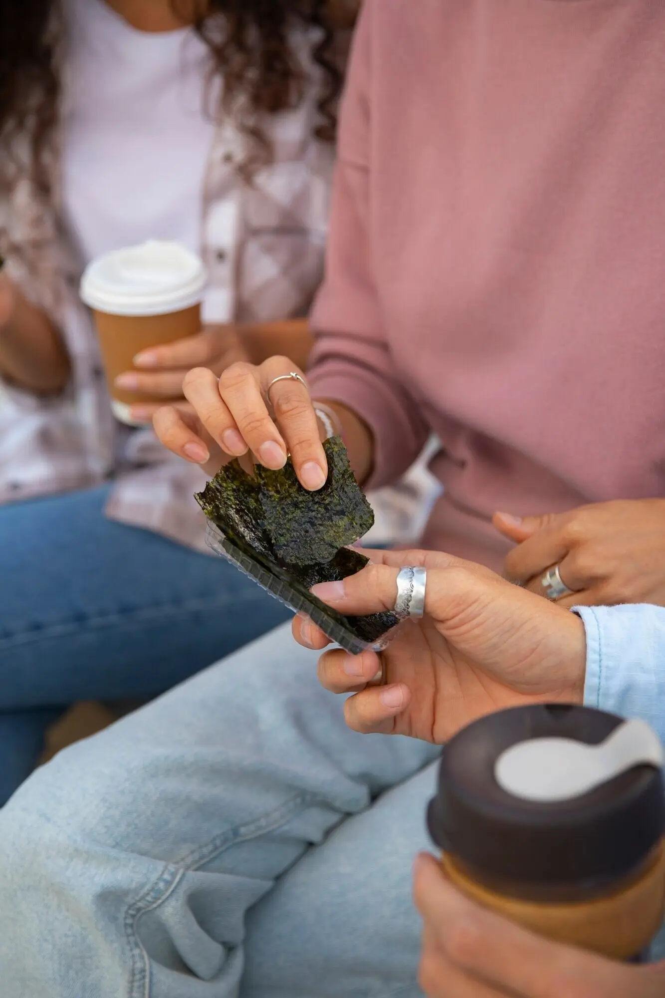 Toma en picado de amigos comiendo snacks de algas marinas.