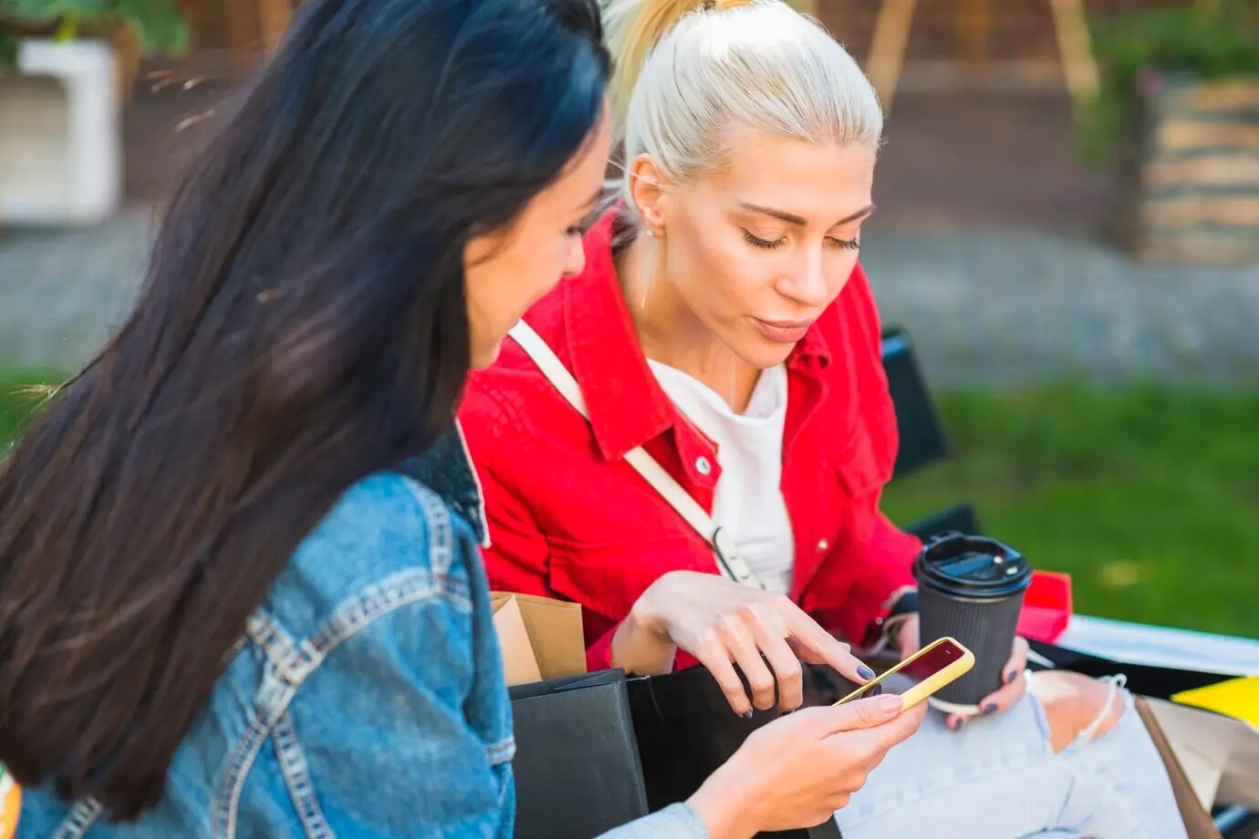 Mujeres mirando un smartphone en un banco en un parque